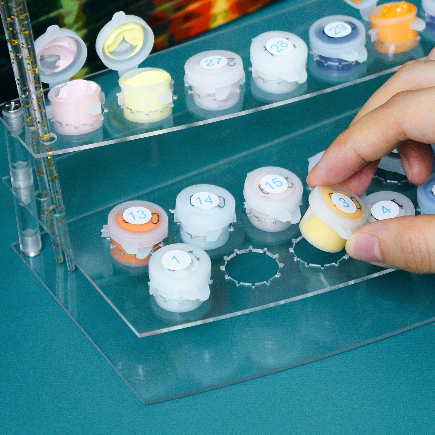 Hand interacting with small containers labeled with numbers on a clear tray.