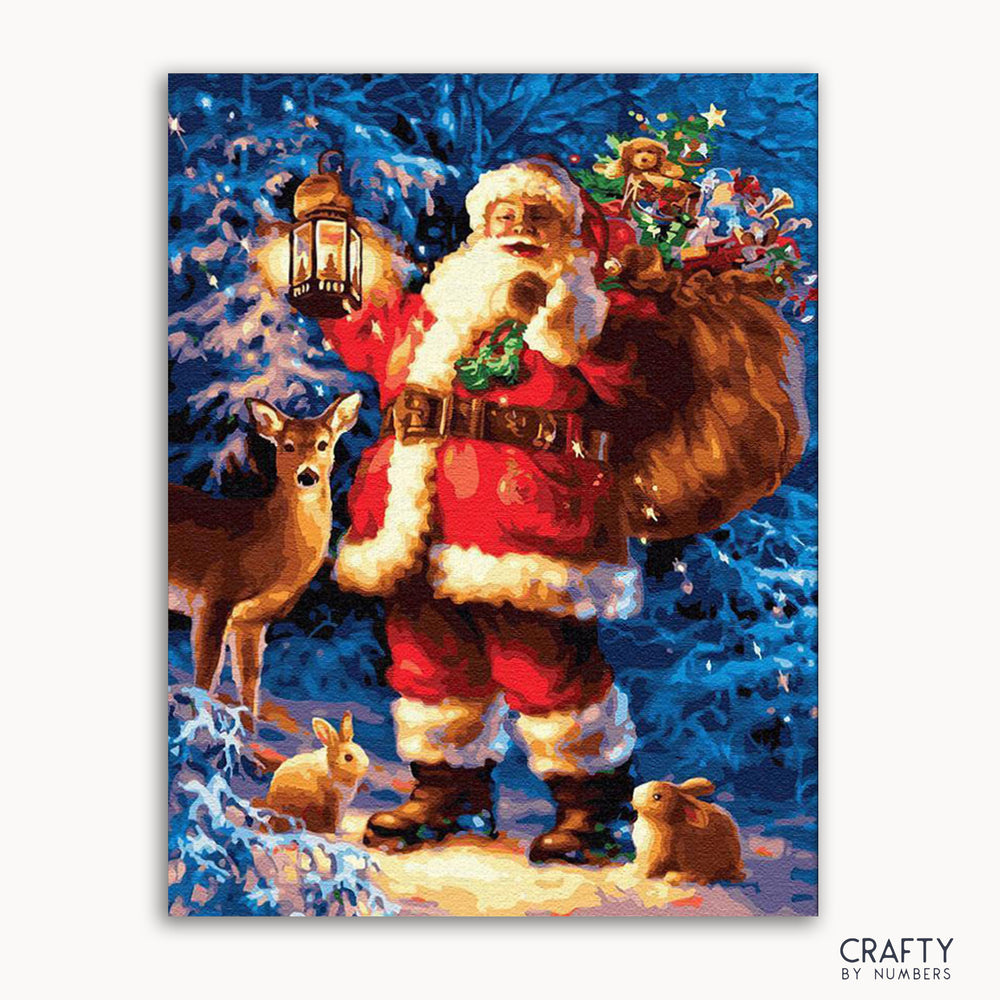 A painting depicting Santa Claus with a lantern, surrounded by deer and rabbits in a snowy landscape. The image has a 'Crafty by Numbers' logo at the bottom.