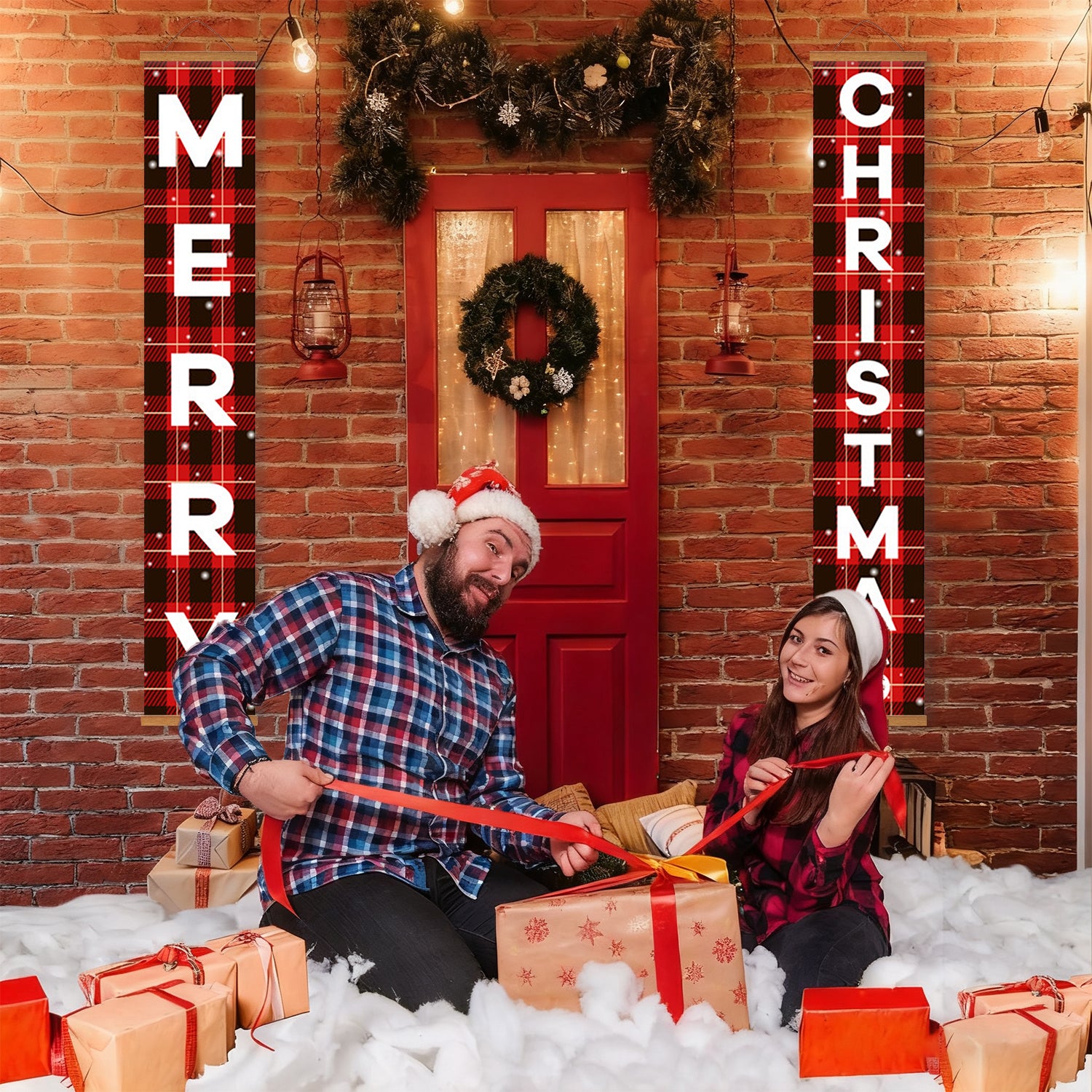 Two people sitting on a snowy floor with Christmas decorations and presents.
