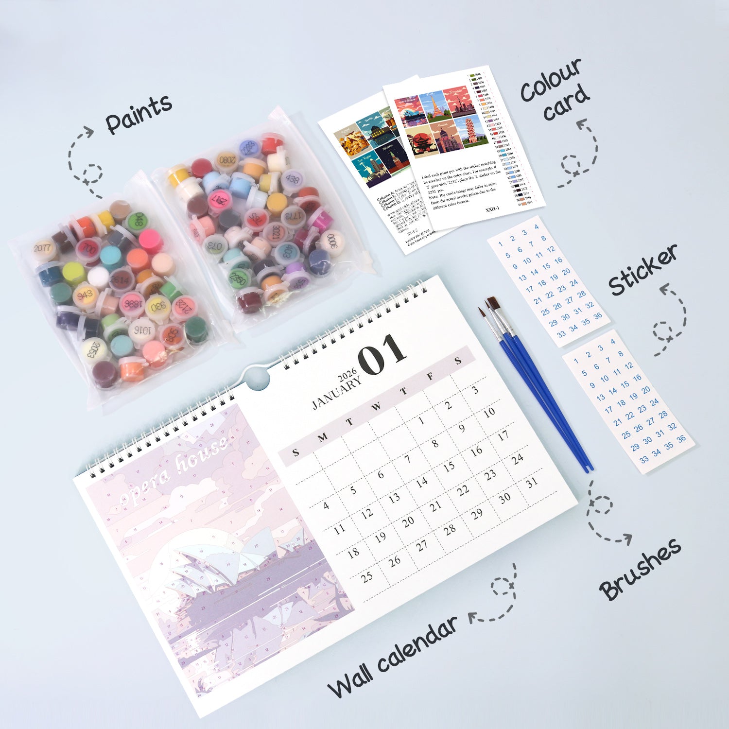 Collection of art supplies including a wall calendar, paint pots, color card, stickers, and brushes on a light blue background.