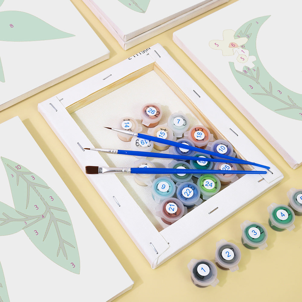 Set of paint tubes and brushes on a white frame with floral designs.