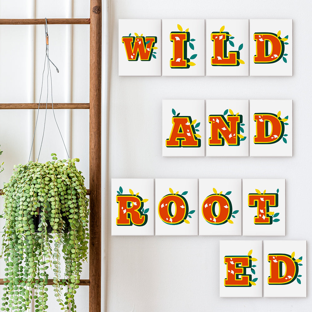 Decorative wall art with 'Wild and Rooted' text on a white wall with a plant.