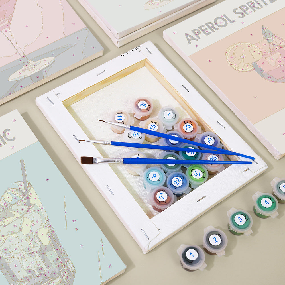 Hand holding a brush painting a mini paint by numbers canvas