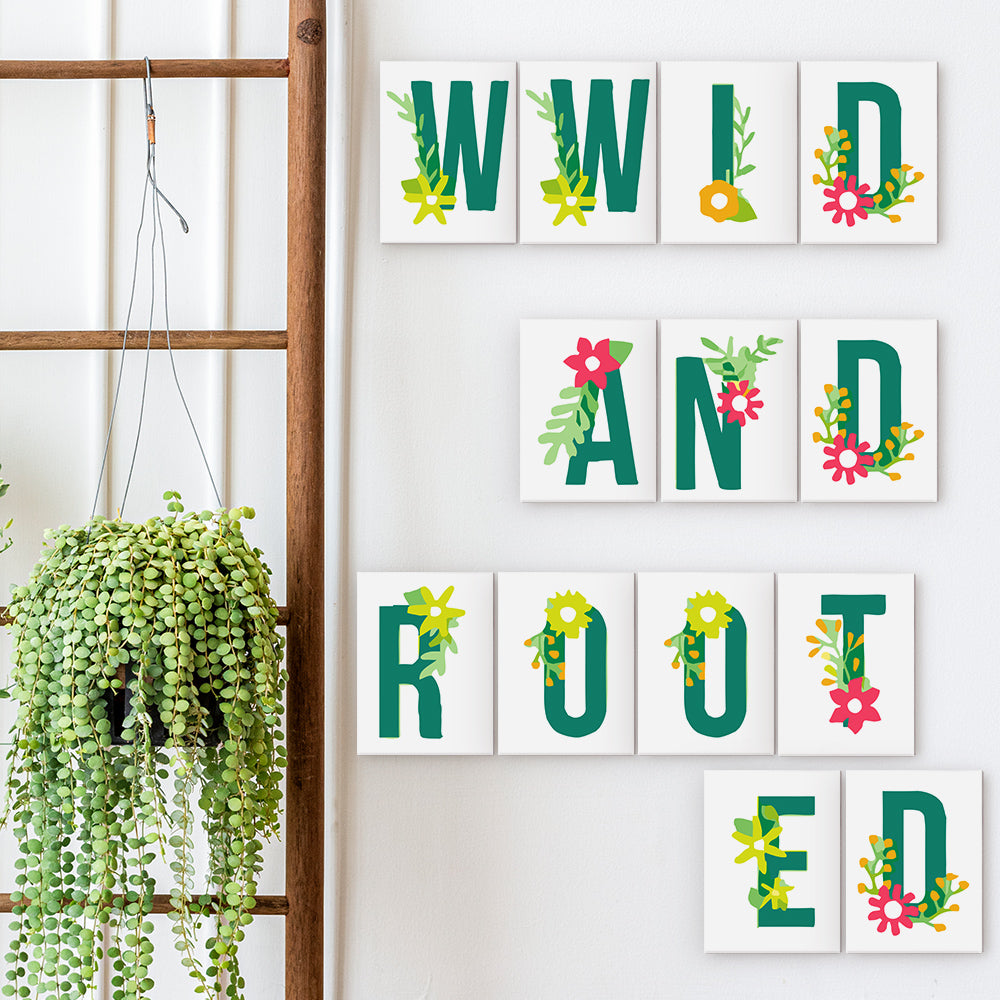 Decorative wall art with colorful letters spelling 'WILD AND ROOTED' on a white wall.
