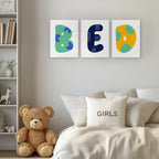 Colorful letters on a wall above a bed with a teddy bear and 'GIRLS' pillow.