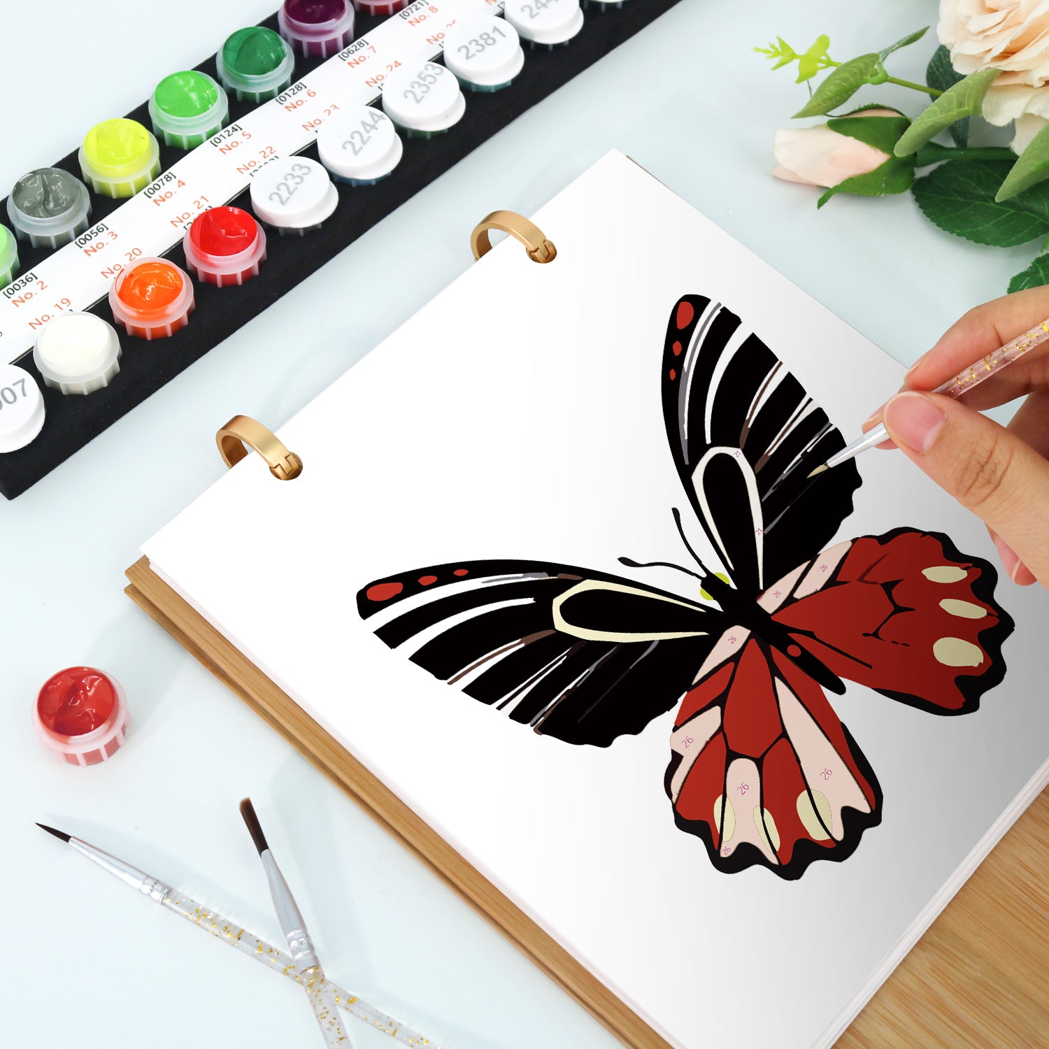 Butterfly drawing on paper with watercolor paints and brushes in the background