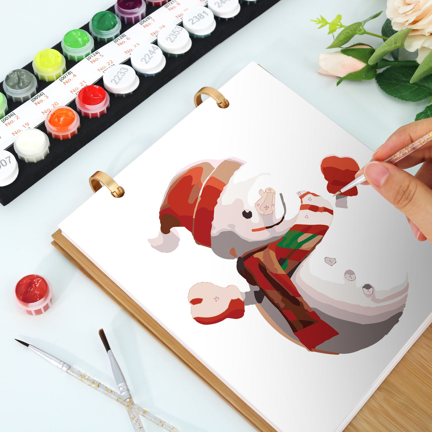 Person, die mit Wasserfarben eine Schneemannillustration auf eine Leinwand malt.