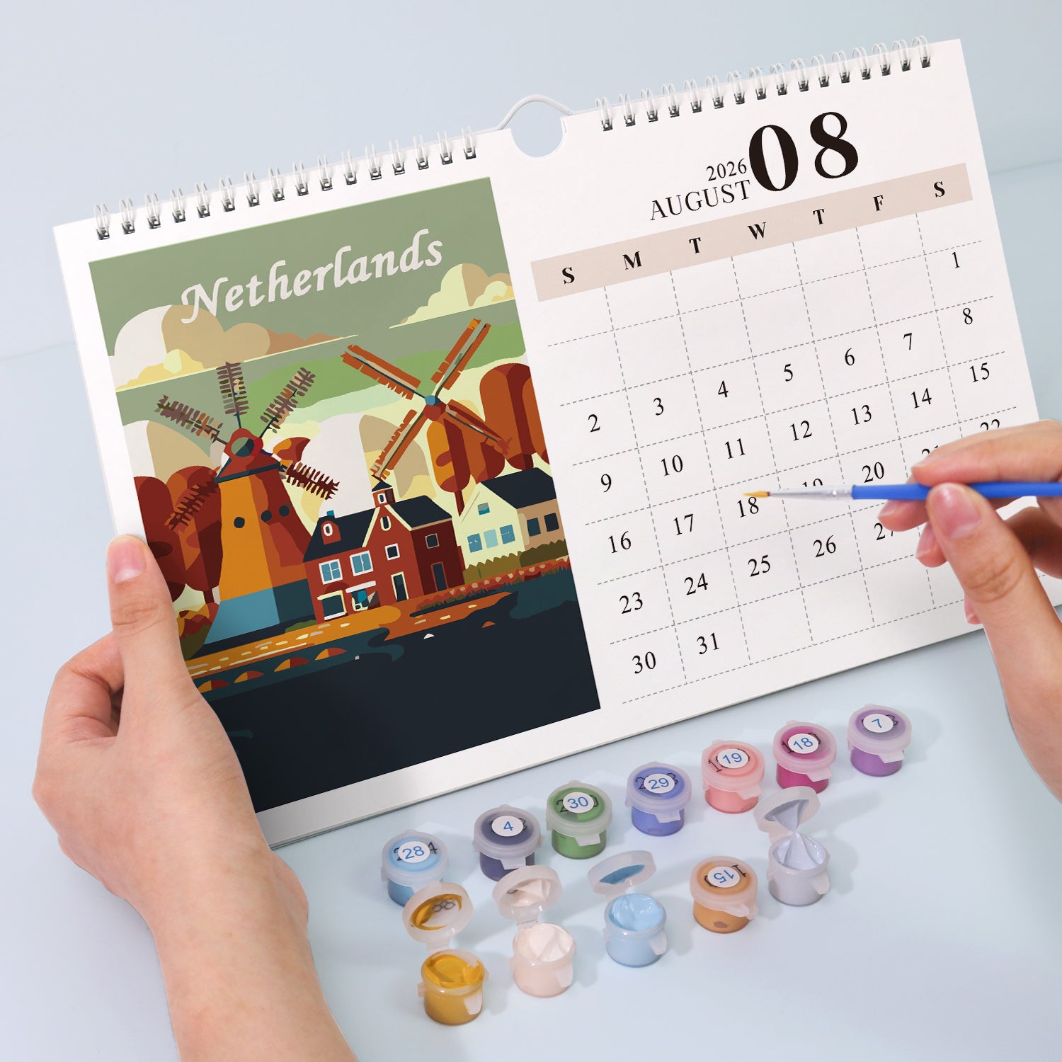 Calendar with a Netherlands design held by hands, surrounded by small containers on a light gray background