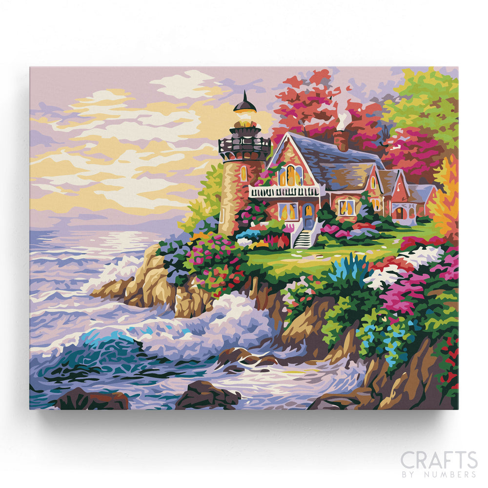 A painting kit depicting a lighthouse with surrounding colorful flowers and a house, set against a backdrop of the sea and sky.