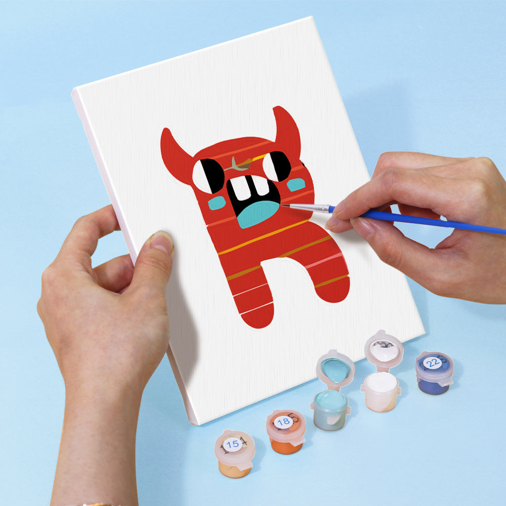 Person painting a red cartoonish creature on a white canvas with paint containers below.