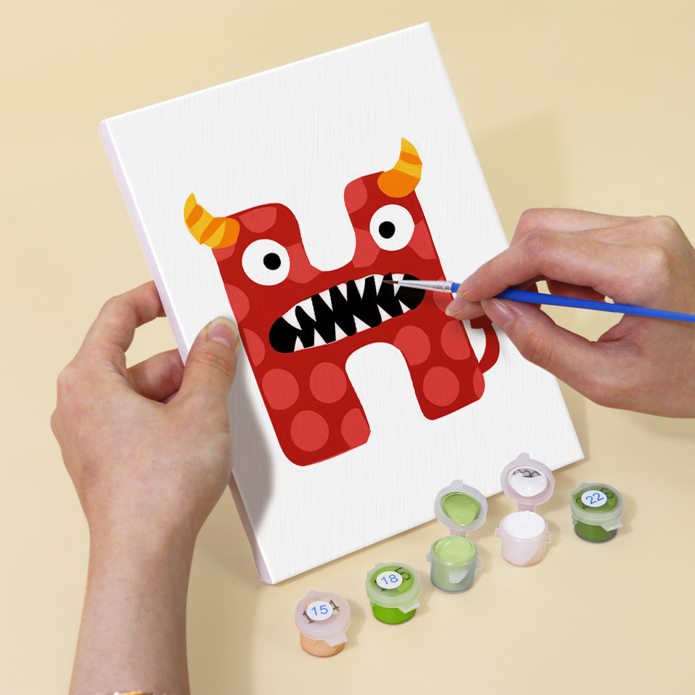 Person painting a red monster on a white canvas with paint supplies on a beige background