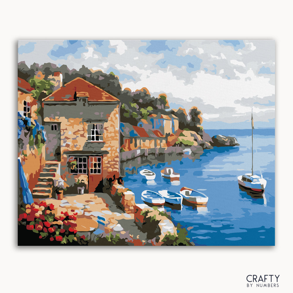 A paint-by-numbers kit depicting a maritime scene with boats and buildings by the sea, labeled 'CRAFTY by NUMBERS'.