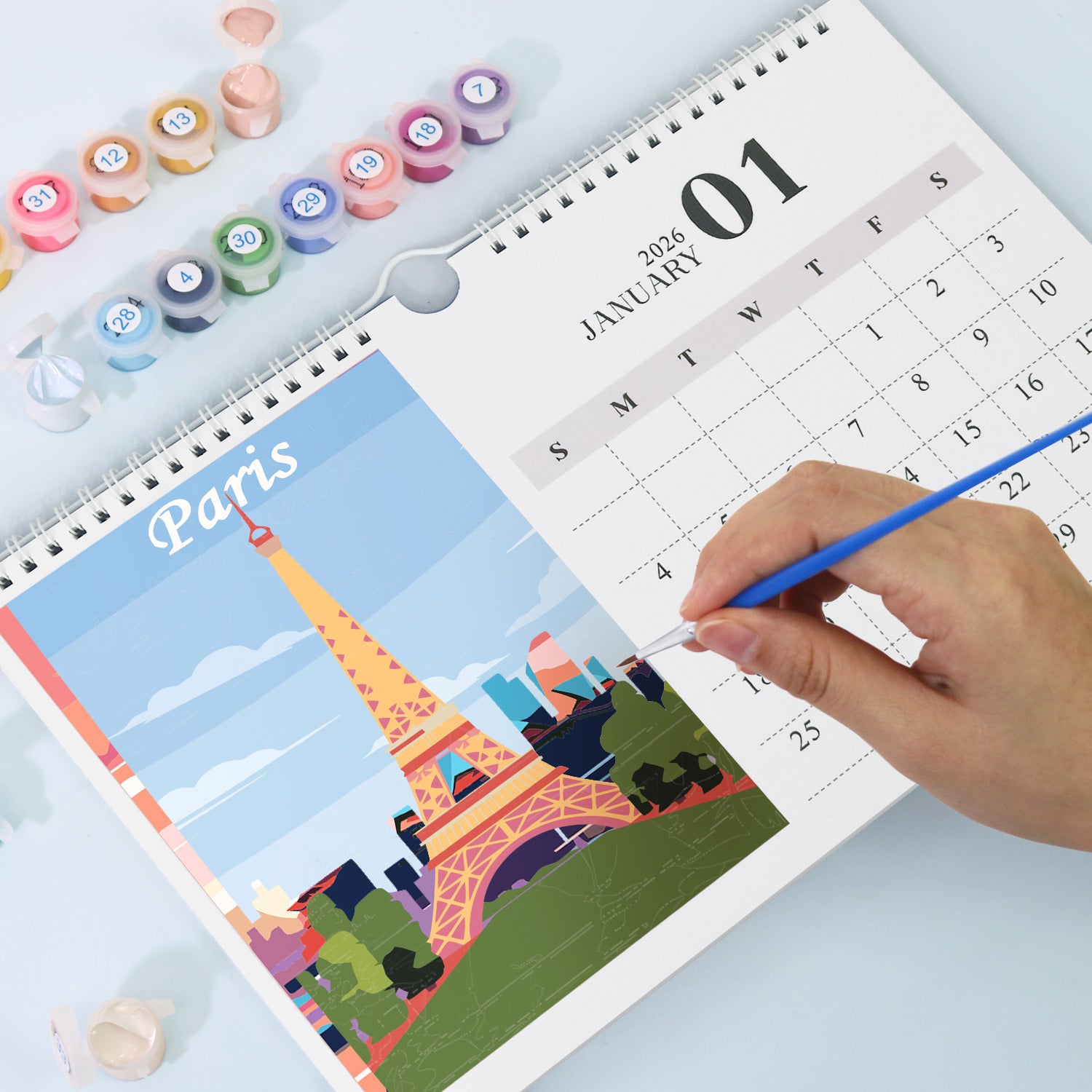 Person coloring a Paris-themed page in a calendar with markers.