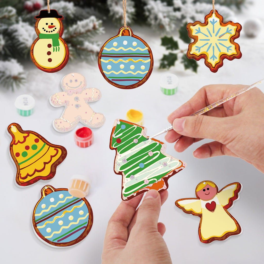 Colorful Christmas-themed cookies being decorated with icing on a white surface.