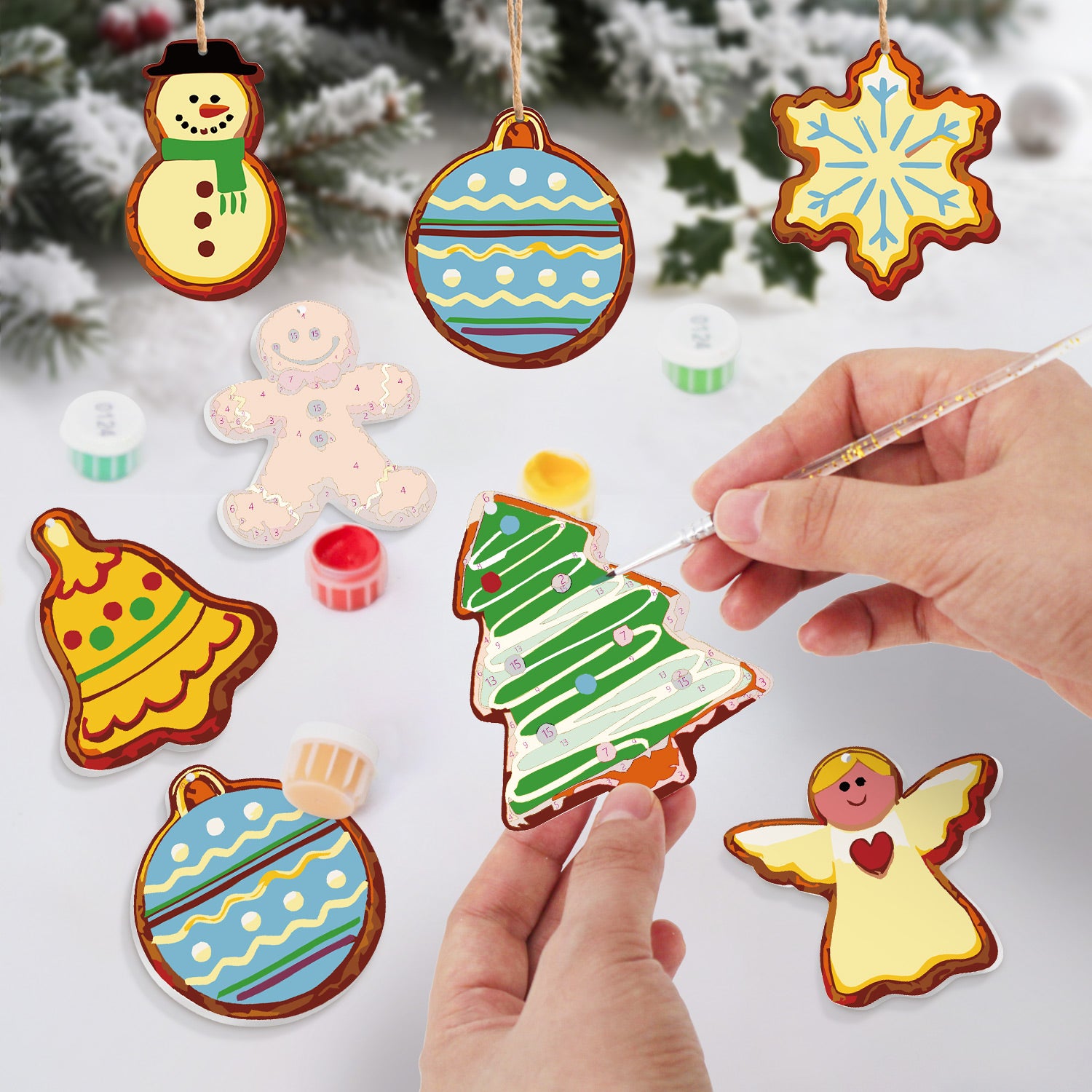 Colorful Christmas-themed cookies being decorated with icing on a white surface.