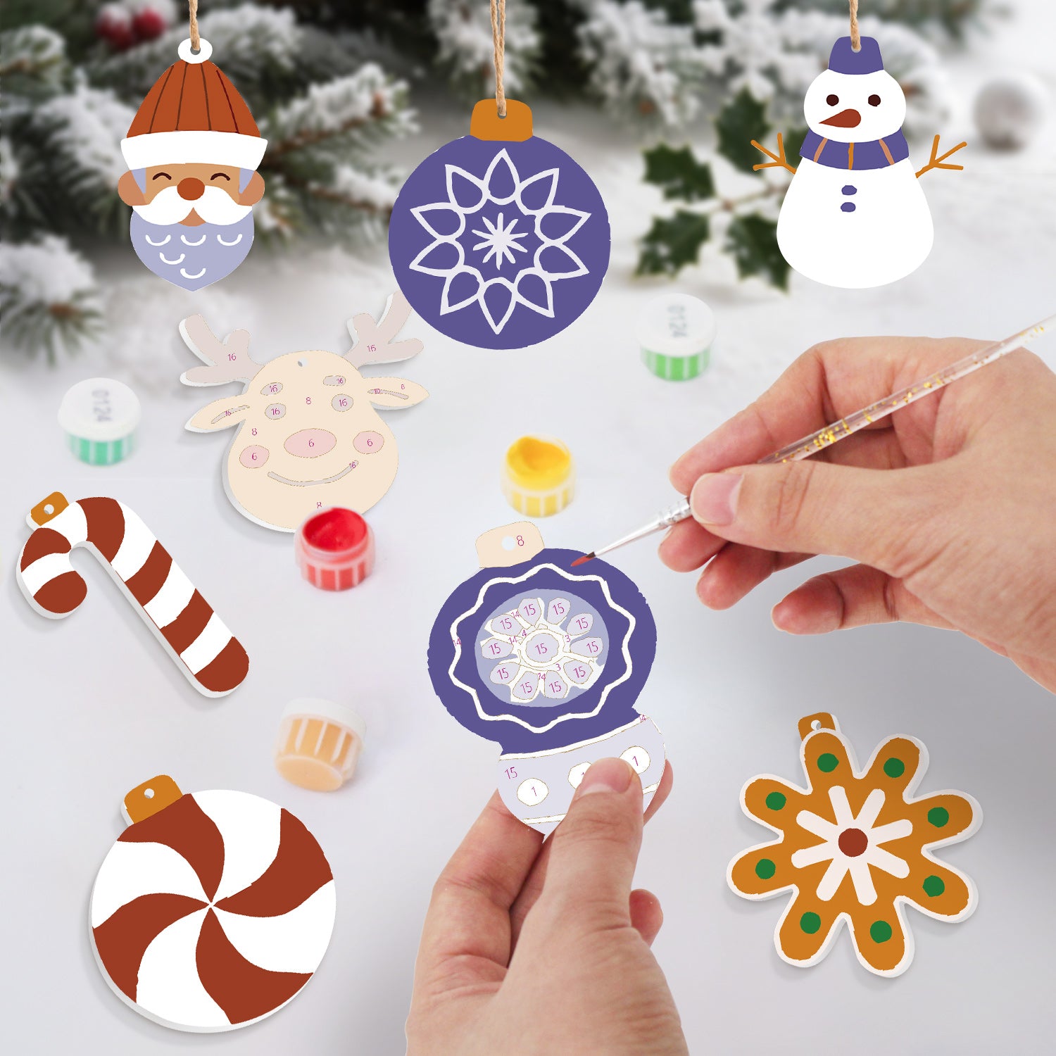 Decorative Christmas ornaments being painted with a hand holding a paintbrush.
