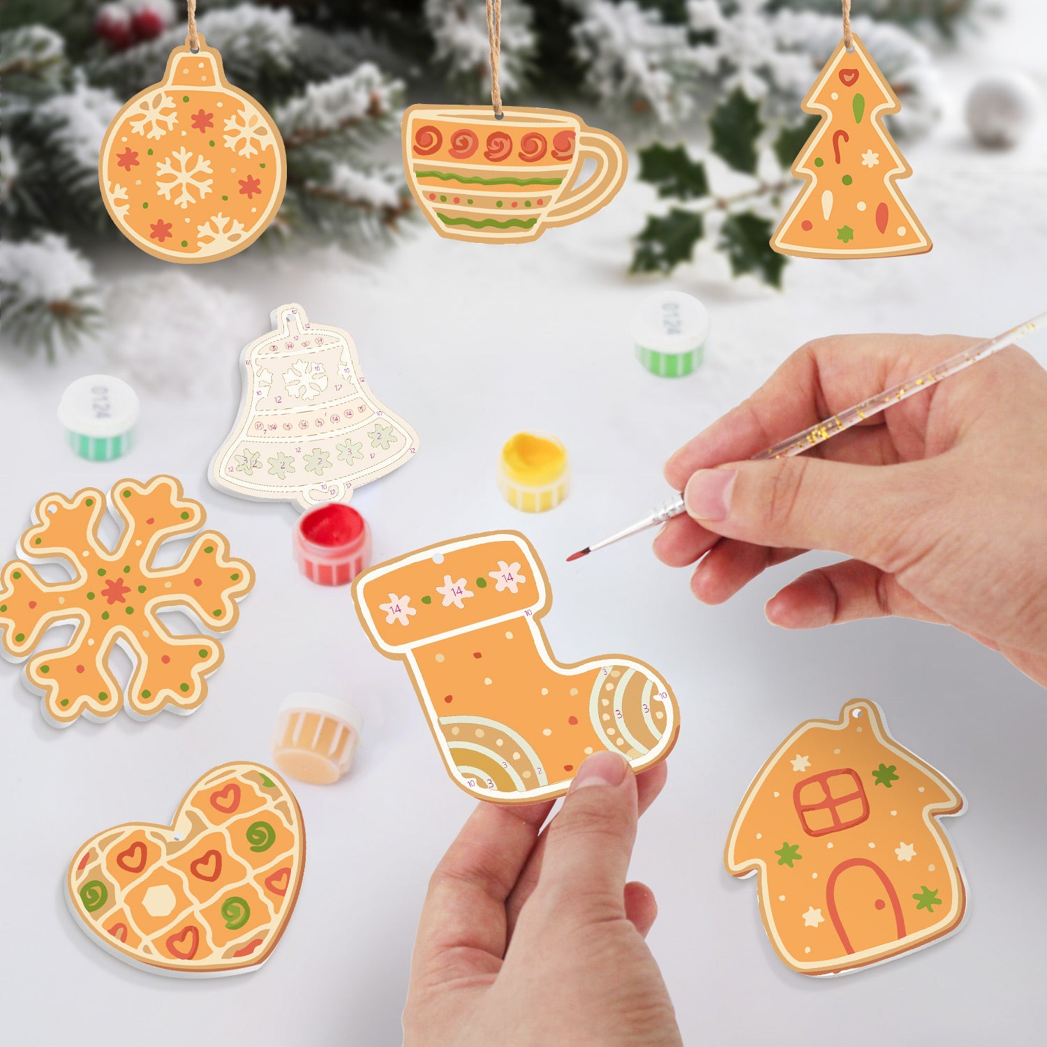Décorations de Noël faites à la main peintes sur une surface blanche avec un fond enneigé.
