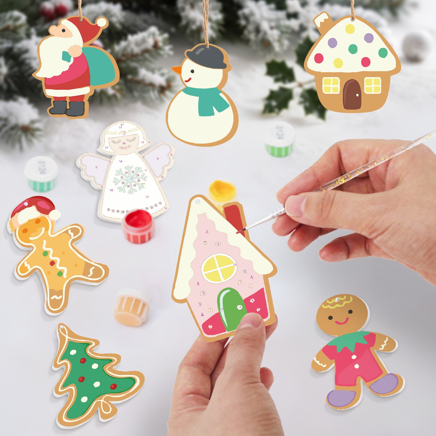 Adornos navideños decorativos pintados sobre una superficie blanca con un fondo nevado.