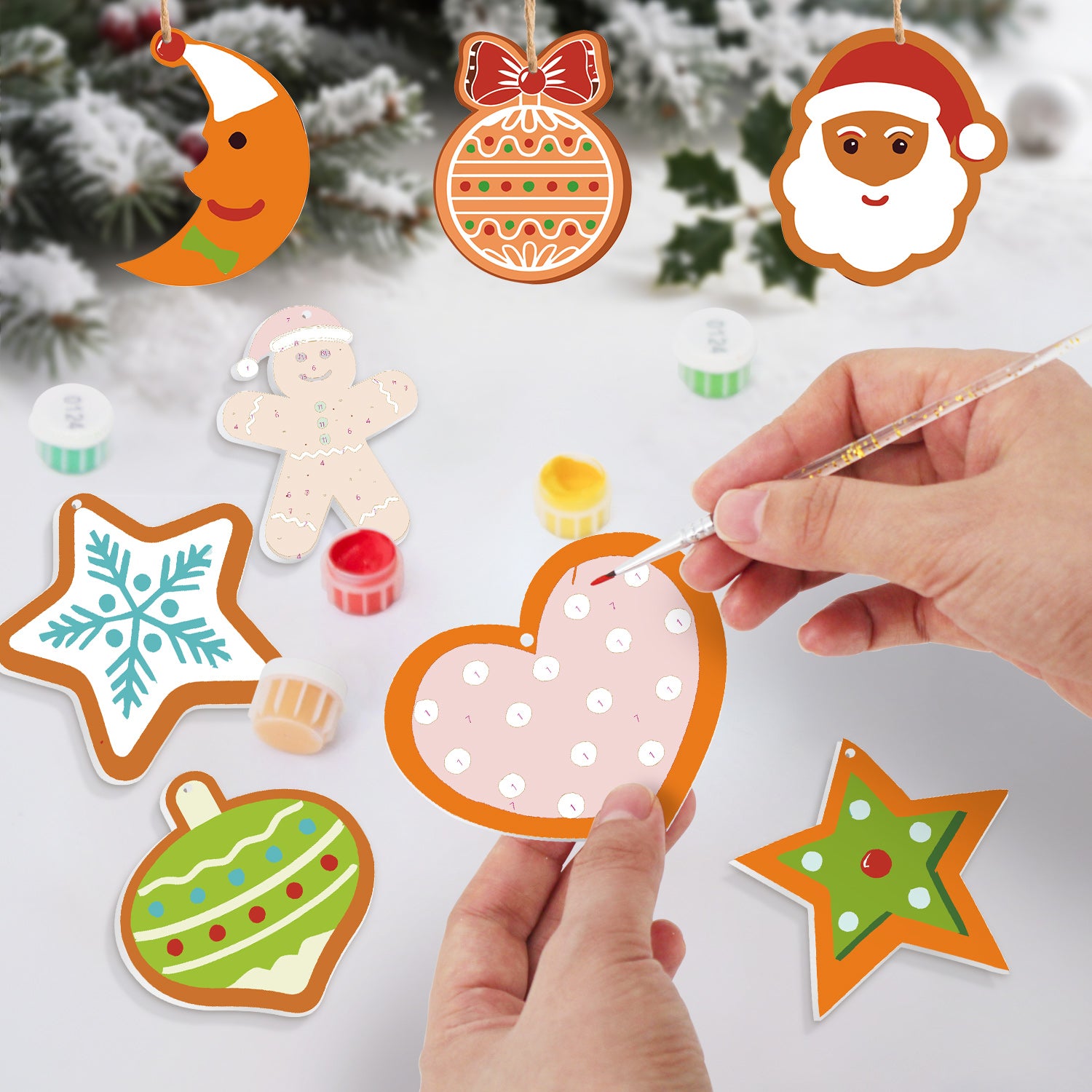 Hand-painted Christmas-themed decorations on a white surface with a snowy background.