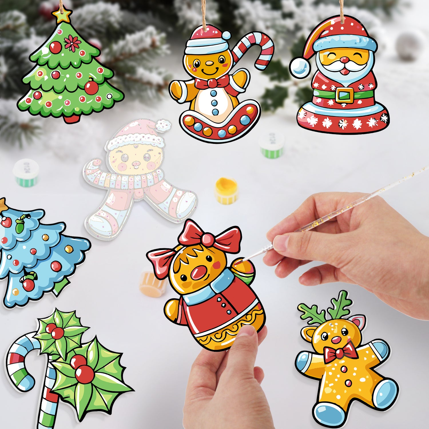 Colorful Christmas-themed paper cutouts with a hand holding one, set against a snowy background.