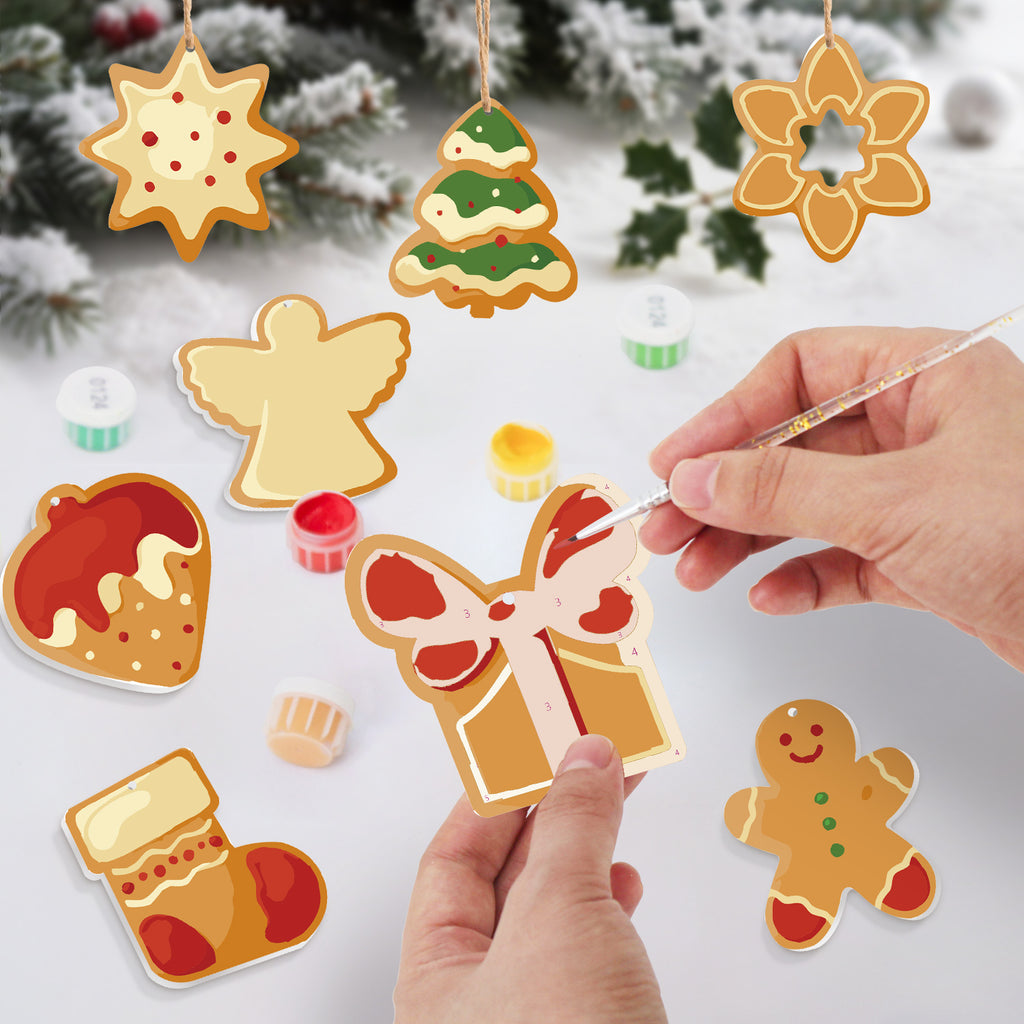 Decorative gingerbread cookie ornaments being painted with a hand holding a paintbrush.