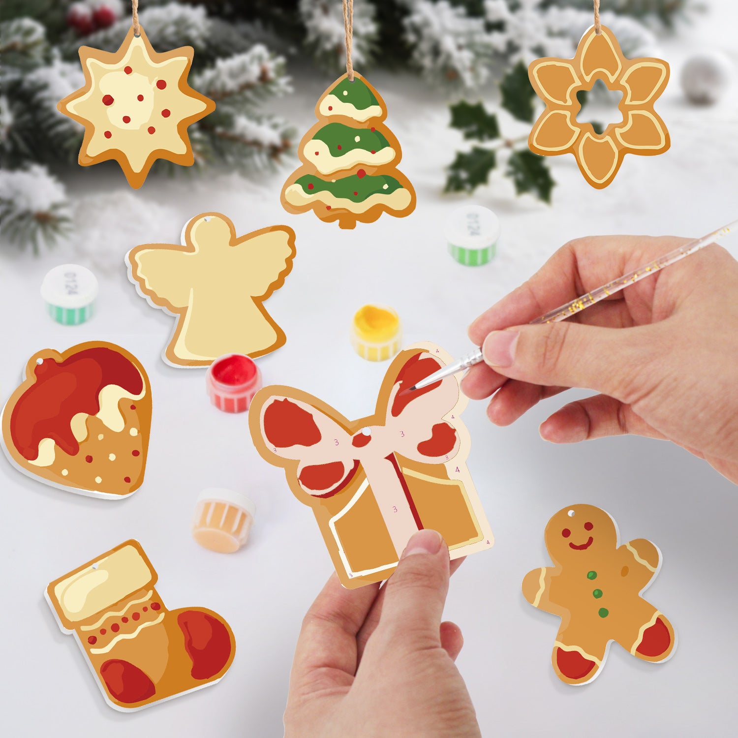 Decorative gingerbread cookie ornaments being painted with a hand holding a paintbrush.