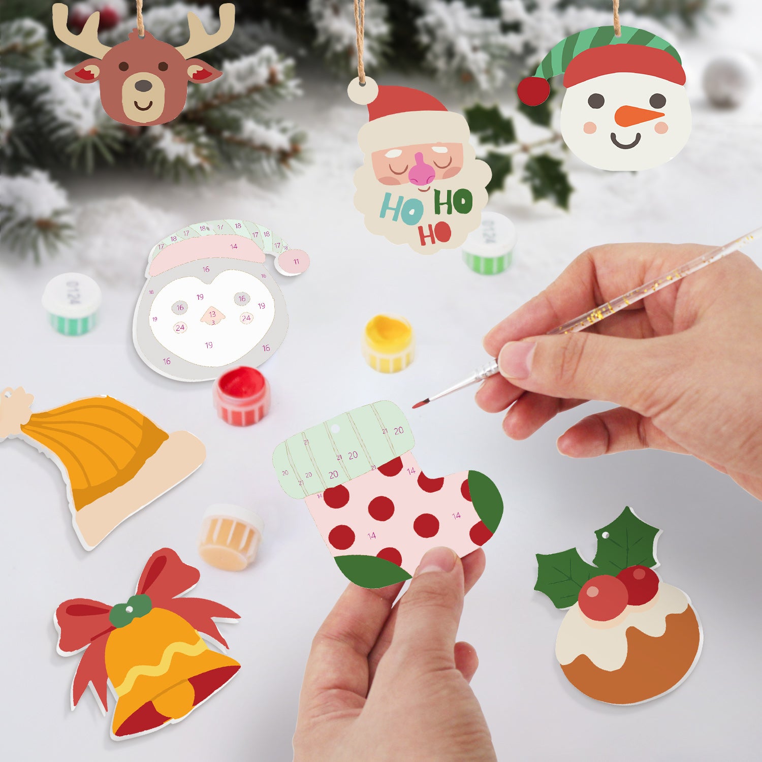 Handmade Christmas ornaments being painted with a brush on a white surface.