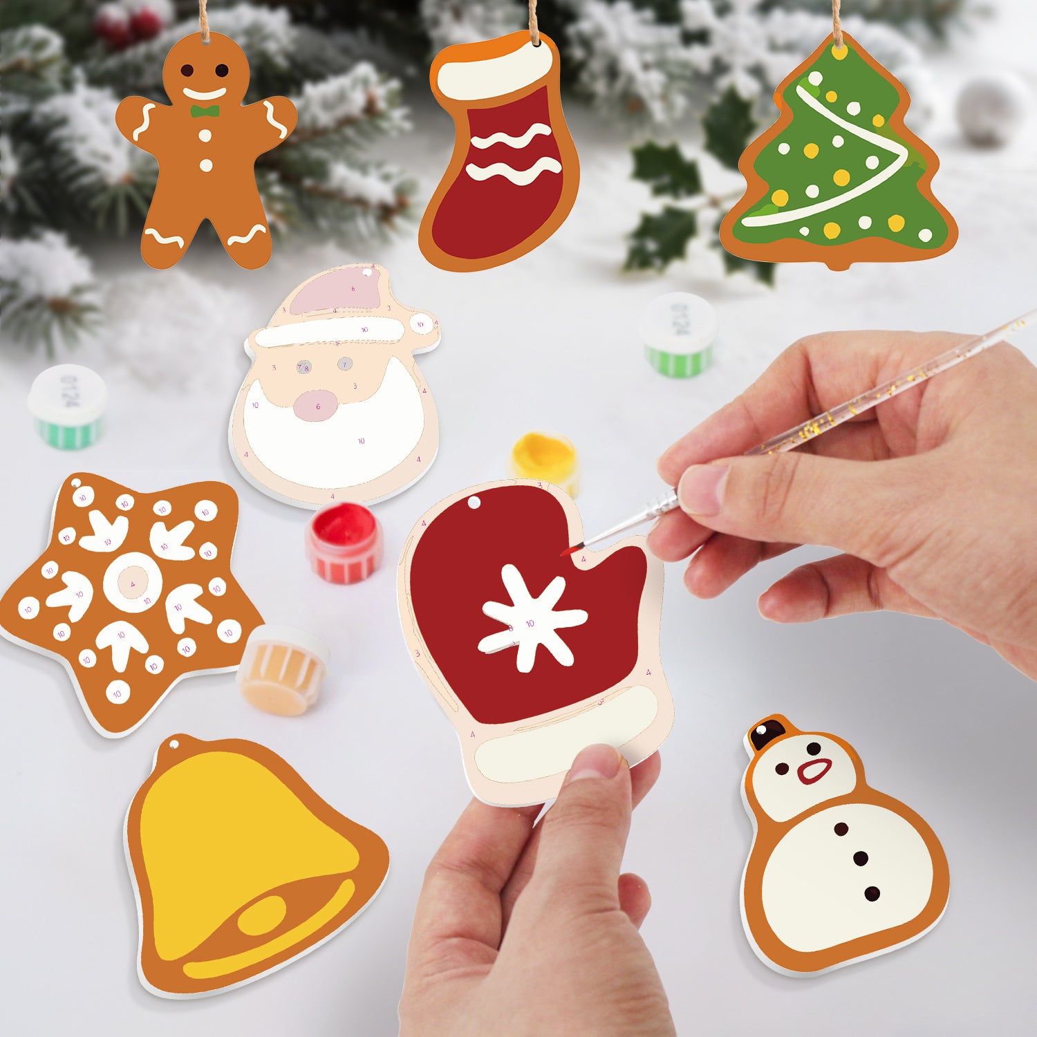 Biscuits sur le thème de Noël peints à la main avec une personne utilisant un pinceau.