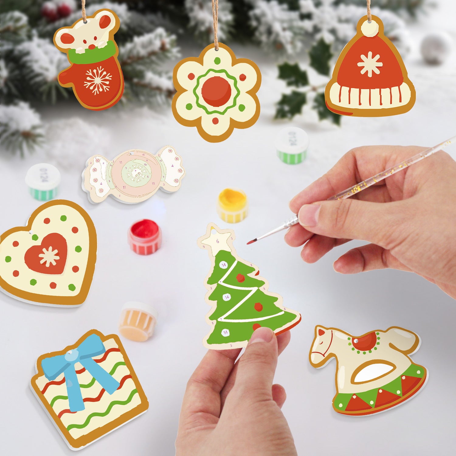 Bunte, weihnachtliche Ausstecherdekorationen, von denen eine Hand bemalt ist.