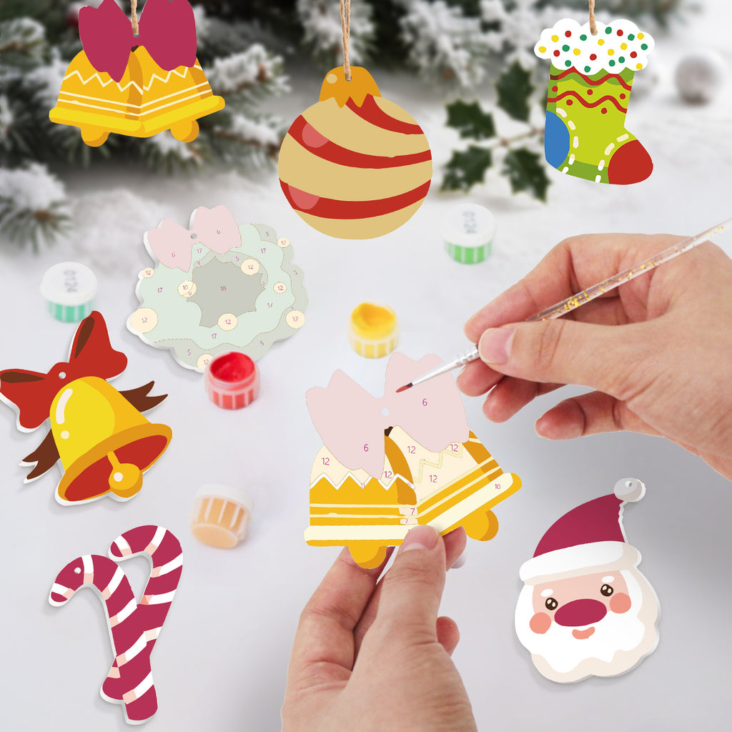 Colorful Christmas-themed paper ornaments being decorated with a paintbrush on a snowy background.