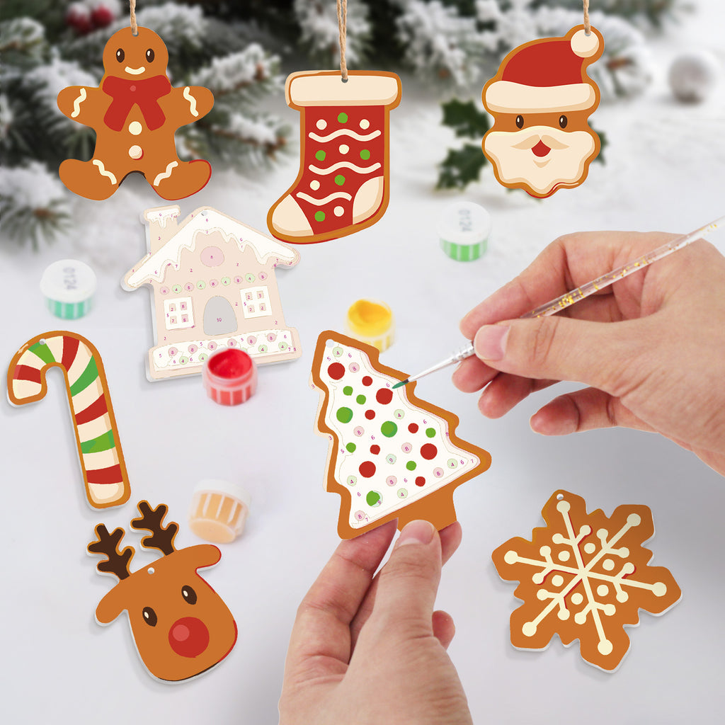 Decorative Christmas ornaments being painted with a hand holding a paintbrush.