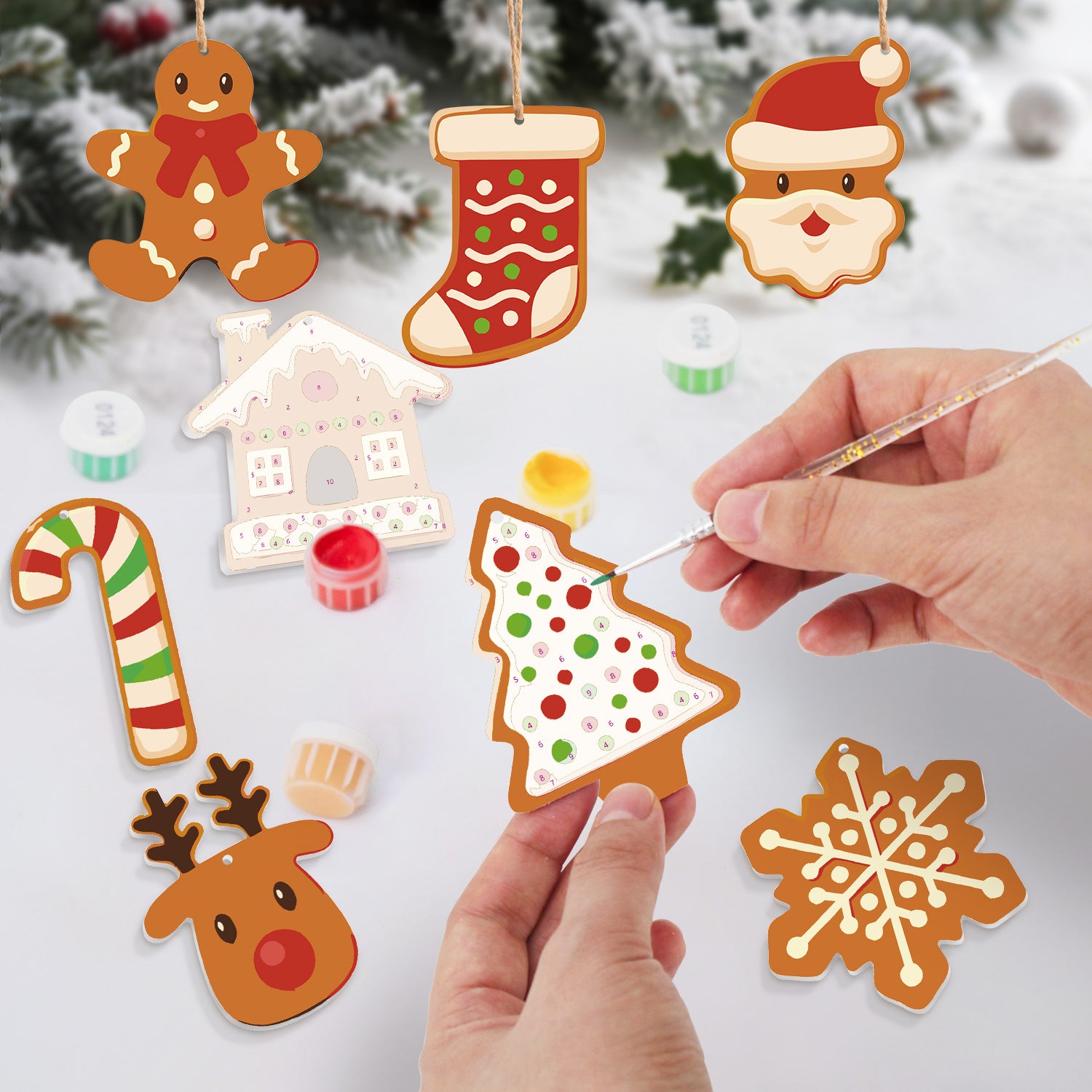 Decorative Christmas ornaments being painted with a hand holding a paintbrush.