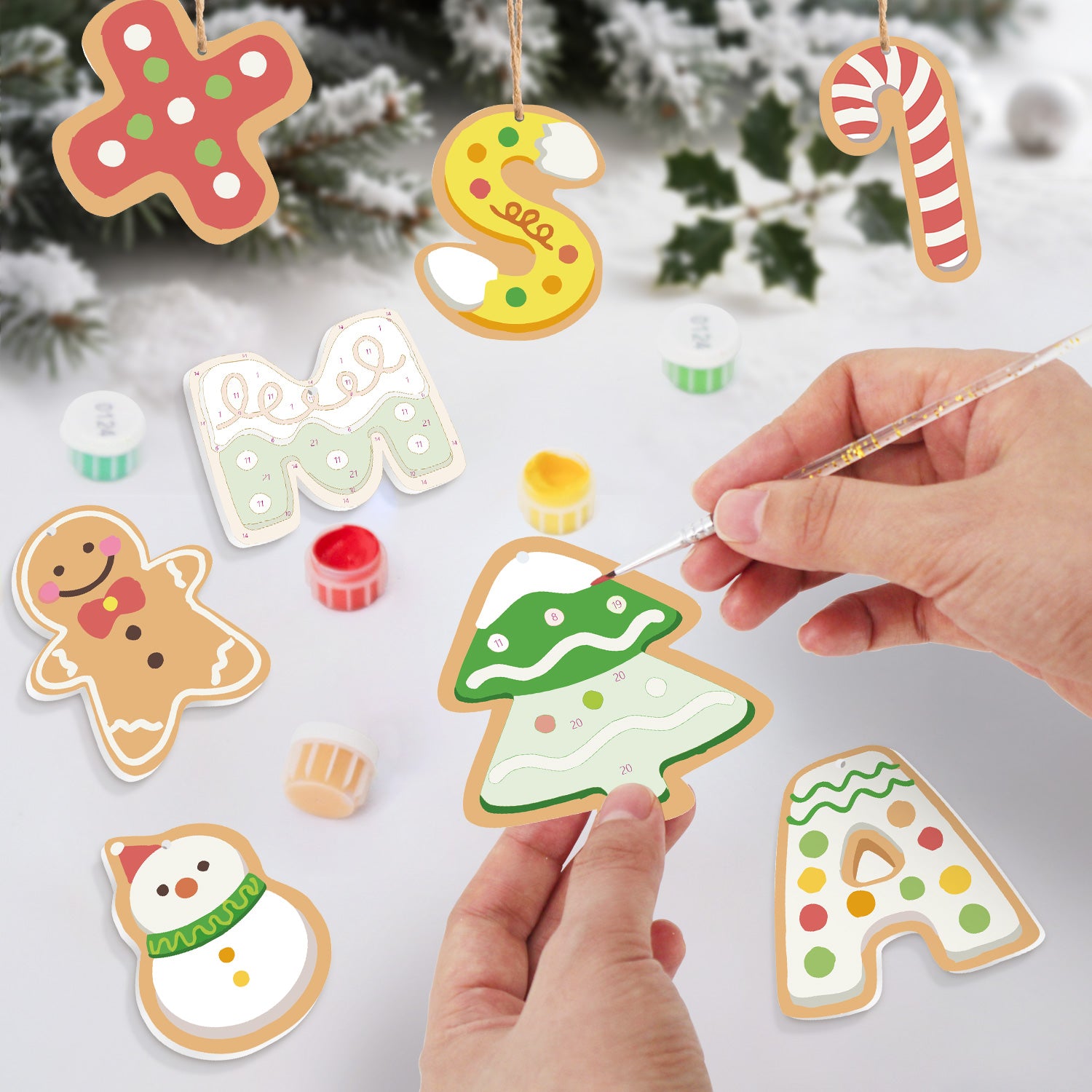 Decorative Christmas cookies being painted with a hand holding a paintbrush.