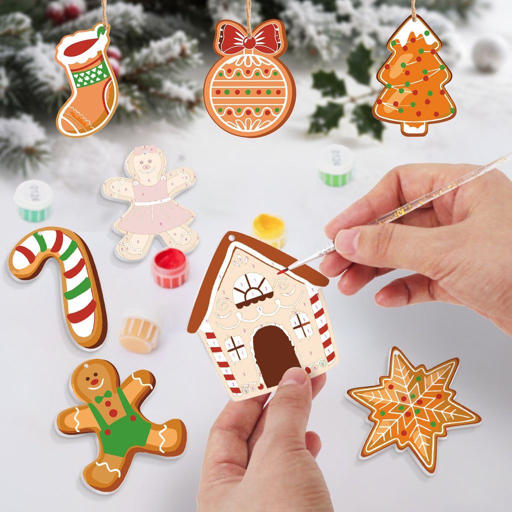 Decorative gingerbread ornaments being painted with a Christmas tree in the background