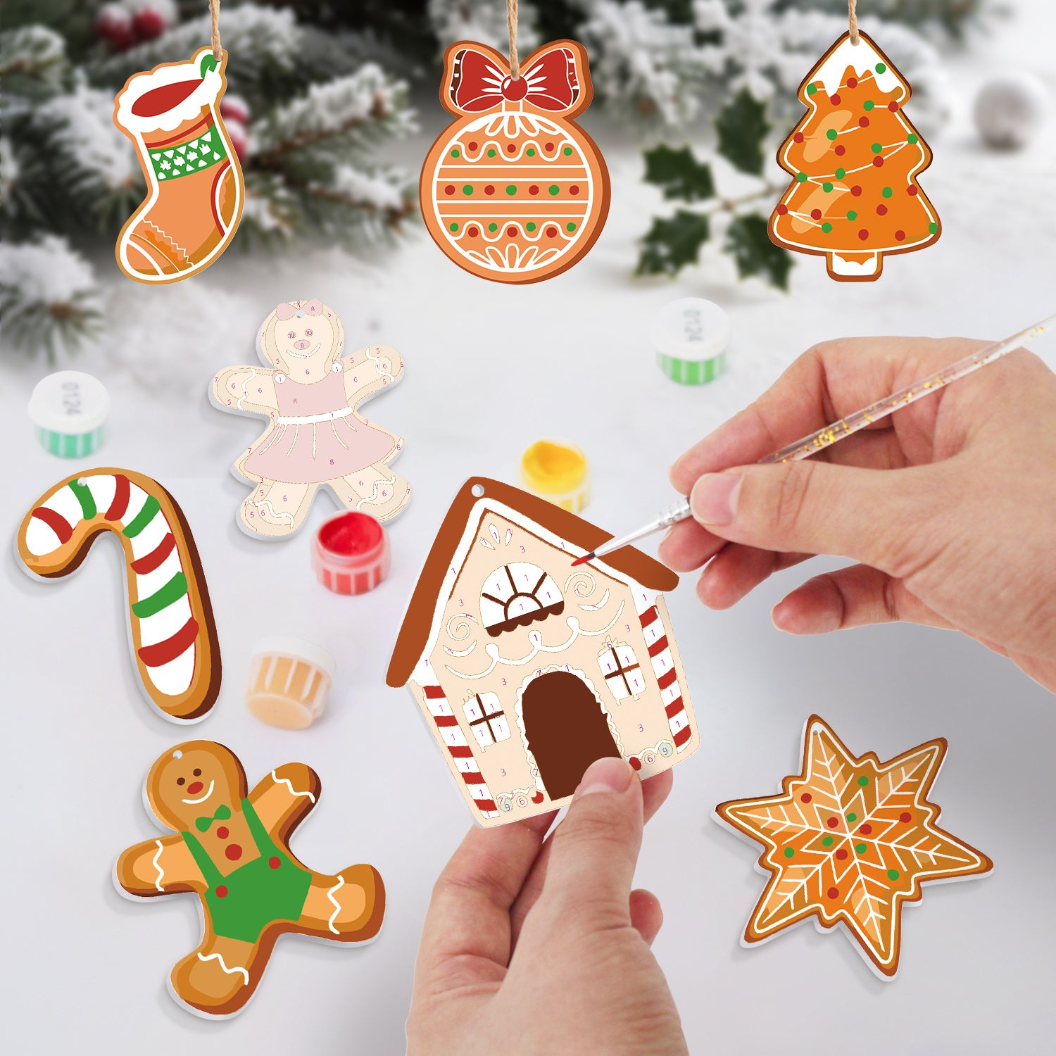 Decorative gingerbread ornaments being painted with a Christmas tree in the background