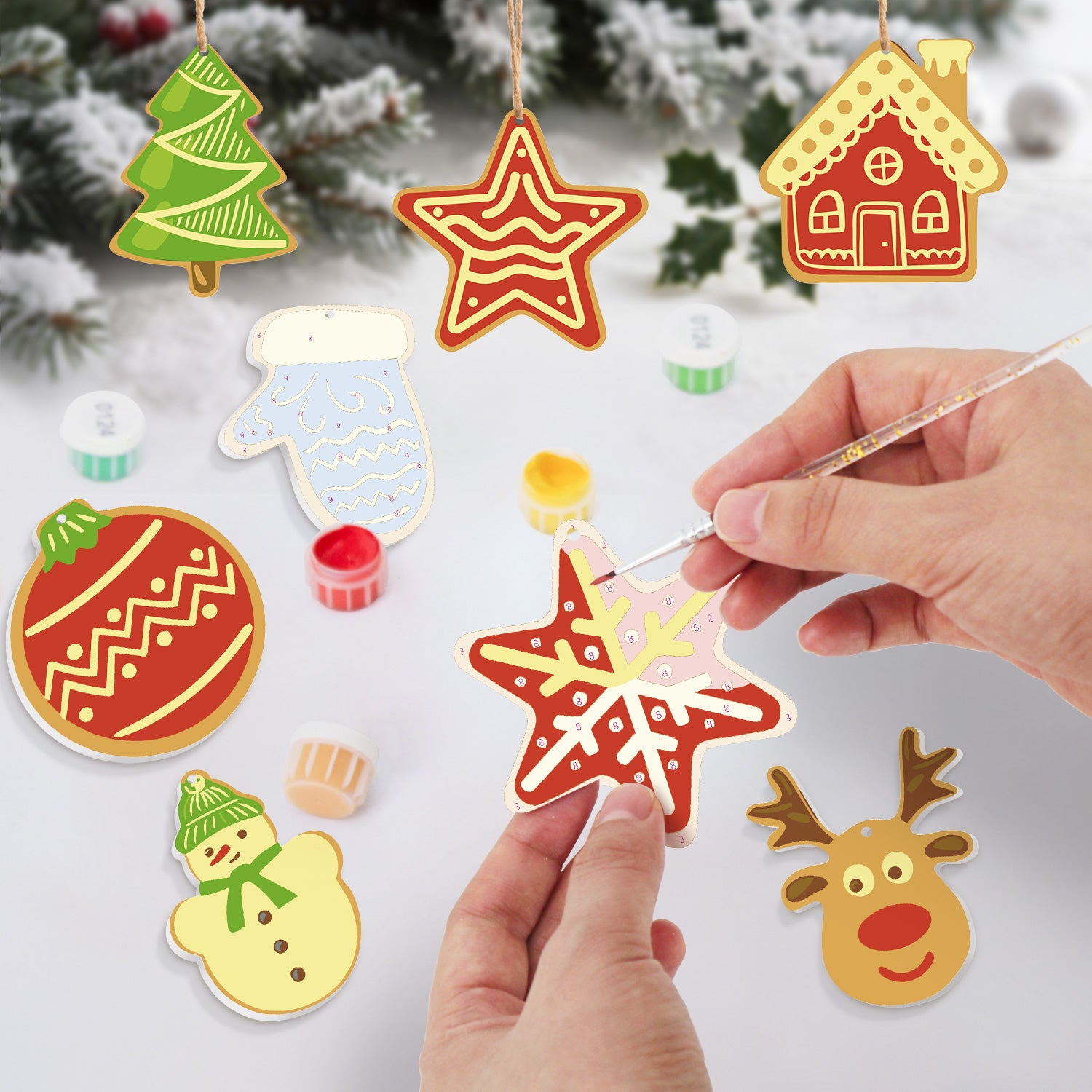 Colorful Christmas-themed paper cutouts with a hand using a paintbrush.