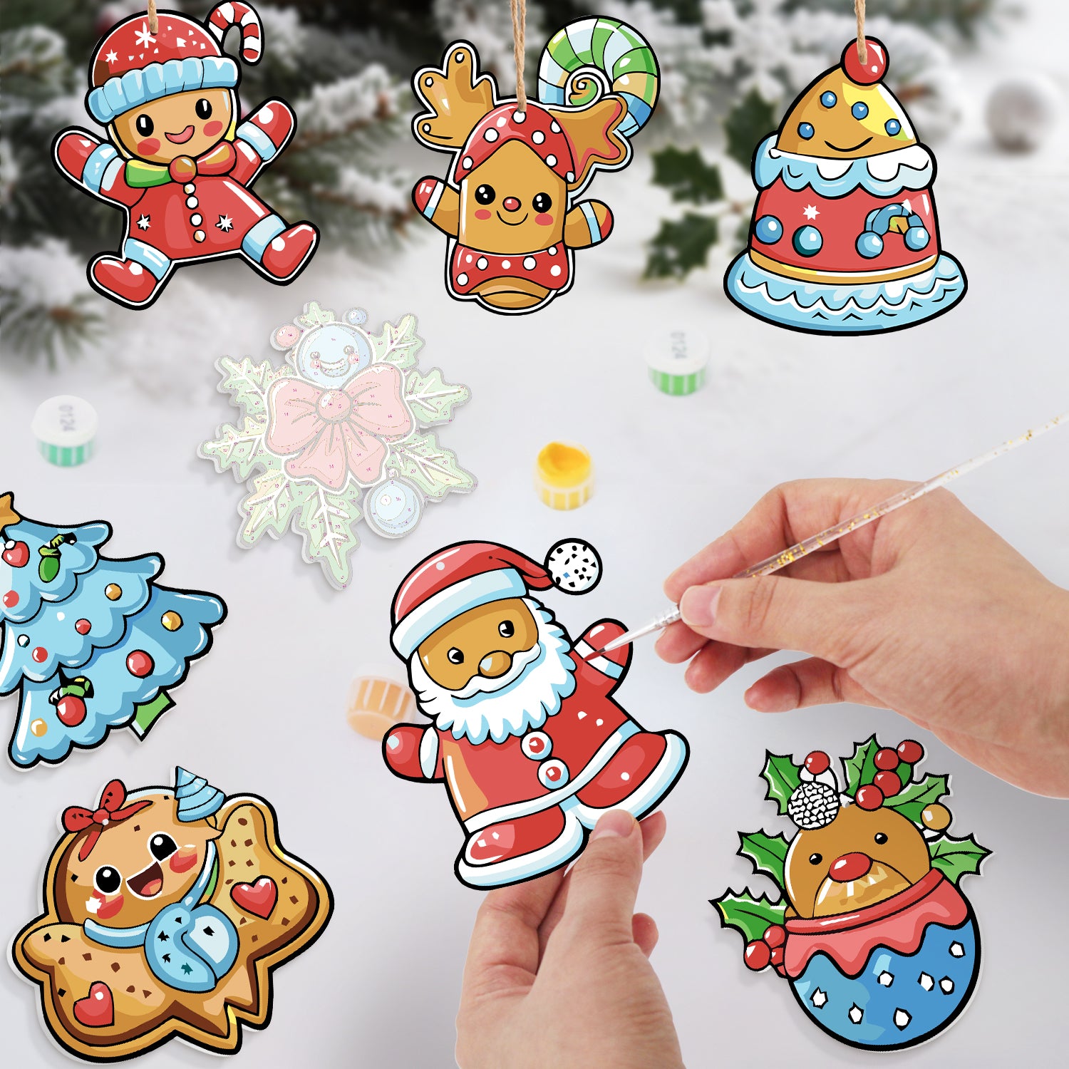 Coloridos recortes de papel con temas navideños sostenidos por una mano sobre un fondo nevado.