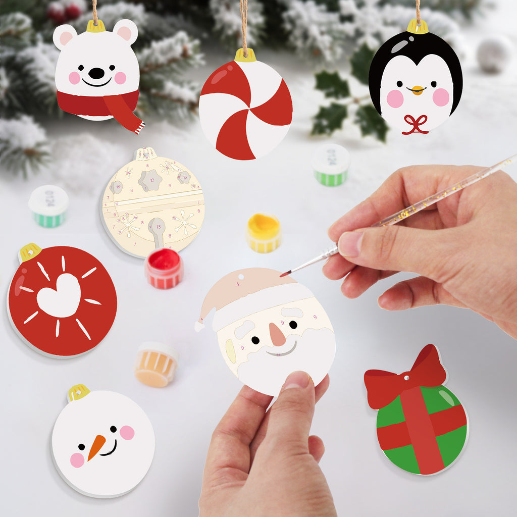 Decorative Christmas ornaments being painted with a hand holding a paintbrush.