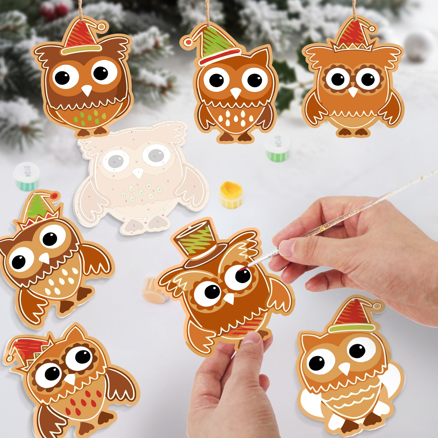 Decorative owl ornaments with festive hats on a snowy background