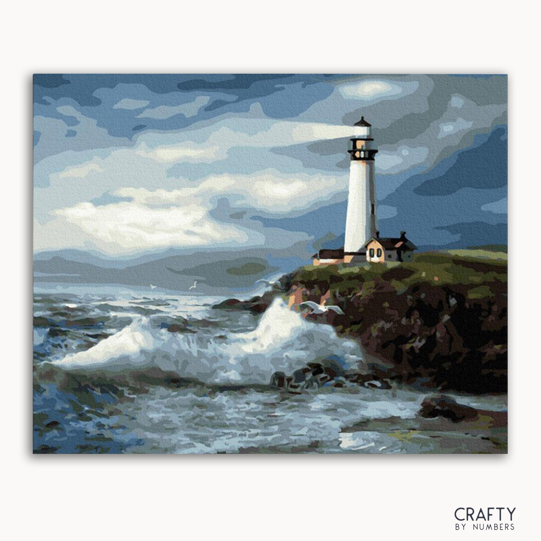 A paint-by-numbers kit depicting a lighthouse with a wave crashing in the foreground, under a blue sky with clouds.