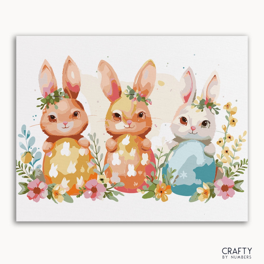 A paint by numbers kit featuring three stylized bunnies with Easter eggs and spring flowers.