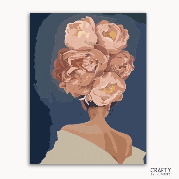 A paint-by-numbers kit image featuring the back of a woman's head with a floral crown in a frame, with the Crafty by Numbers logo at the bottom.