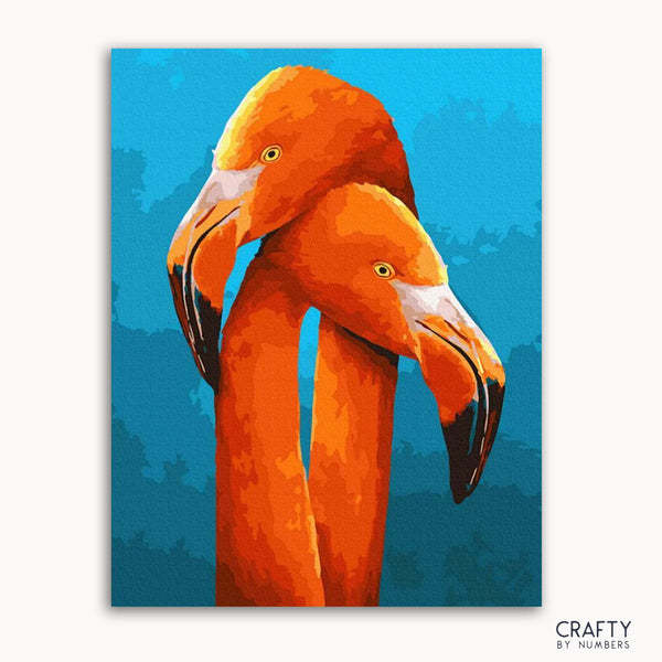 A painting of two orange flamingos with their heads intertwined, set against a blue background. The painting is labeled with 'CRAFTY by numbers'.