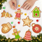 Decorative gingerbread cookies shaped like a house, star, bell, and other festive designs on a white surface with Christmas decorations.