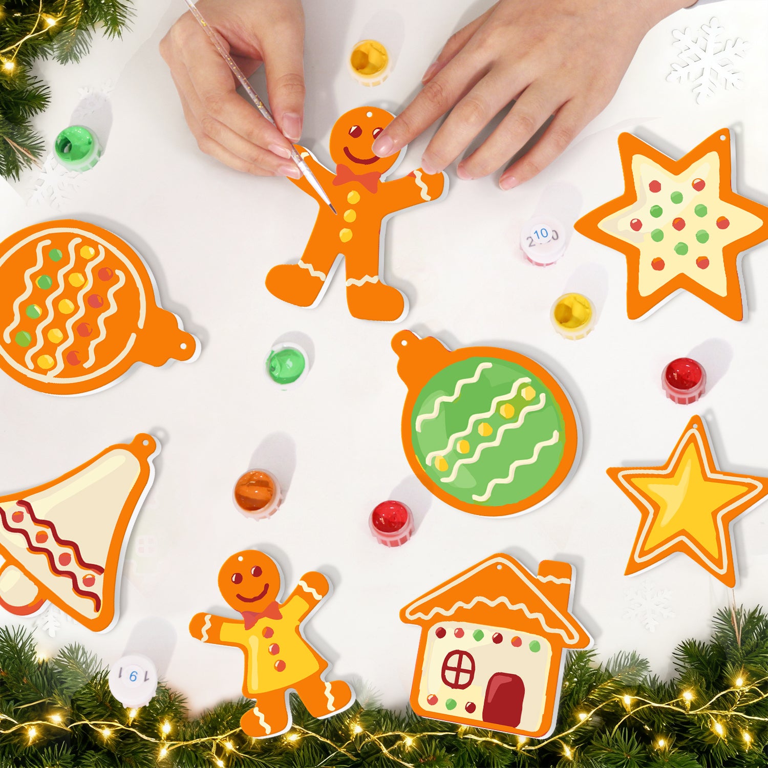 Kinderhände dekorieren weihnachtliche ausgeschnittene Ornamente auf einer weißen Oberfläche mit festlichen Dekorationen rundherum.
