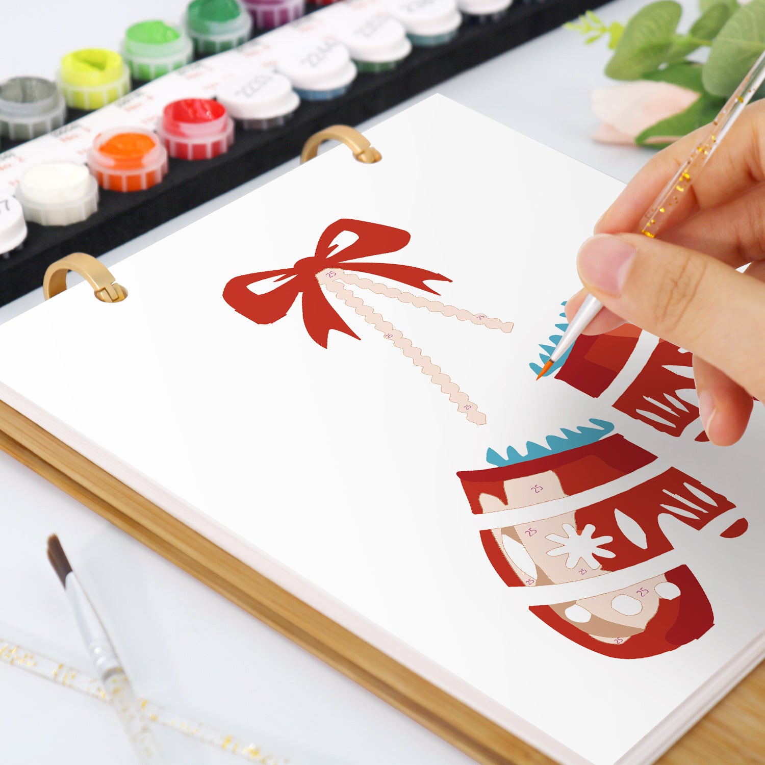 Person painting a Christmas-themed illustration on a canvas with watercolors.