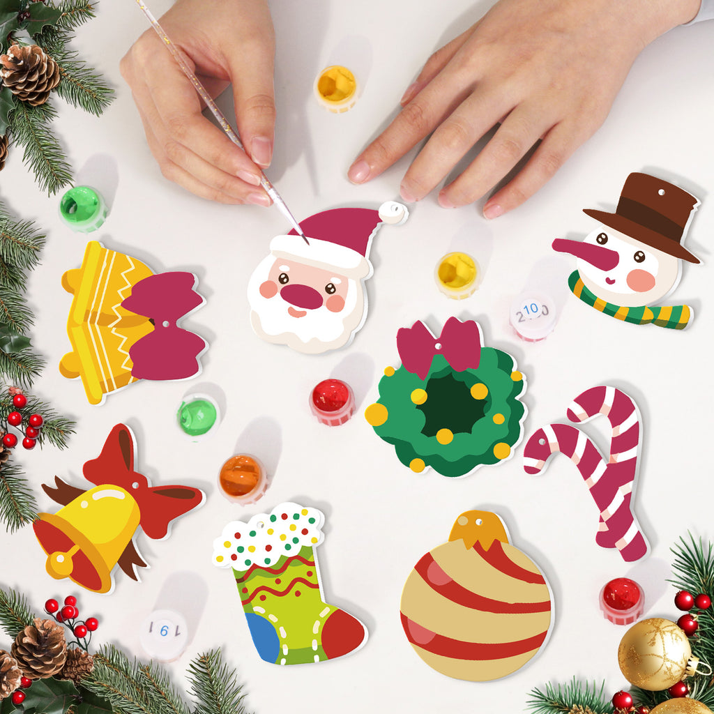 Children's hands painting Christmas-themed ceramic decorations on a white surface with festive elements.
