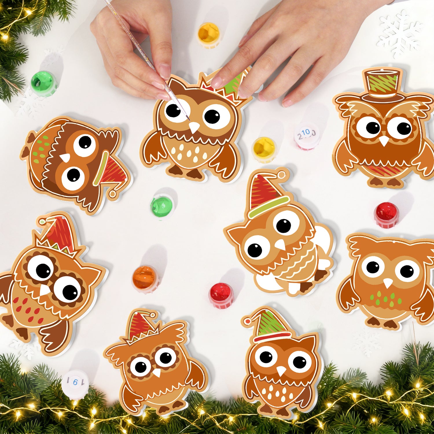 Decorative owl ornaments with festive hats on a white surface with Christmas decorations.