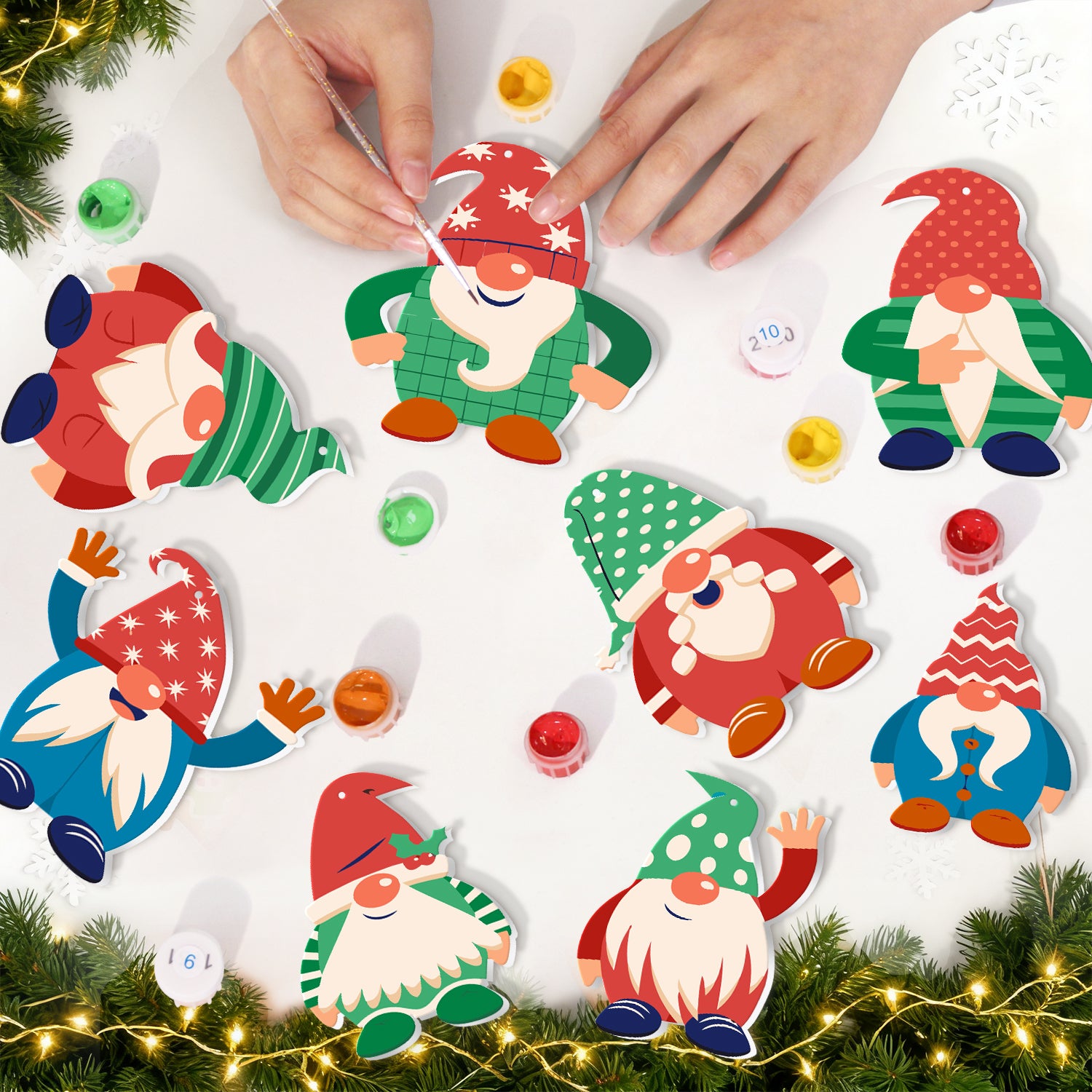 Colorful gnome decorations on a white surface with Christmas lights and greenery.