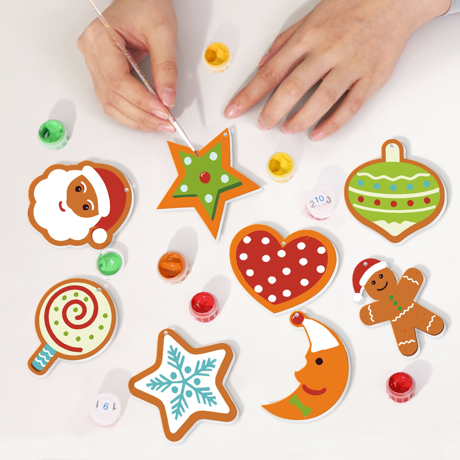 Children's hands decorating Christmas-themed cookies with colorful icing on a white surface.